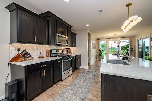 1043 Shore Acres, Columbia, MO 65201 - kitchen with appliances with stainless steel finishes, a sink, a chandelier, decorative backsplash, and recessed lighting
