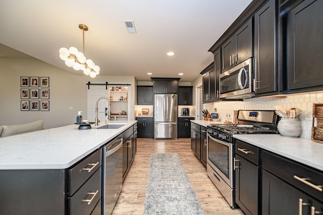 1043 Shore Acres, Columbia, MO 65201 - kitchen featuring stainless steel appliances, a sink, a barn door, light wood-style flooring, and backsplash
