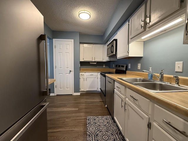 500 Columbia Dr Unit D, Columbia, MO 65203 - kitchen featuring stainless steel appliances, a sink, white cabinetry, dark wood-style floors, and a textured ceiling
