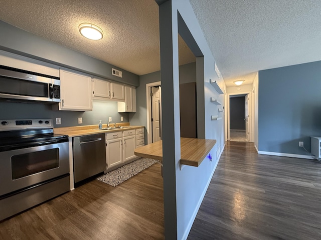 500 Columbia Dr Unit D, Columbia, MO 65203 - kitchen featuring stainless steel appliances, wooden counters, a textured ceiling, and dark wood-type flooring