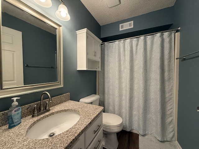 500 Columbia Dr Unit D, Columbia, MO 65203 - bathroom featuring vanity, toilet, a textured ceiling, wood finished floors, and a shower with curtain