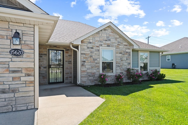 15620 Allegiance Ave, Ashland, MO 65010 - view of exterior entry with stone siding, roof with shingles, and a lawn