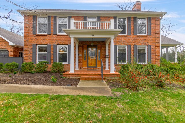 404 S Greenwood Ave, Columbia, MO 65203 - colonial home featuring a balcony, brick siding, a chimney, covered porch, and a front yard