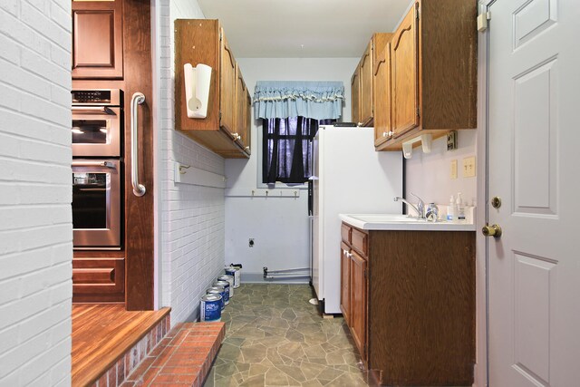 404 S Greenwood Ave, Columbia, MO 65203 - washroom featuring a sink, dark stone finish floors, and brick wall