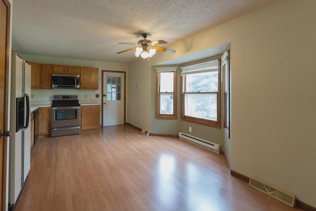 606 Wientz St, Moberly, MO 65270 - kitchen featuring appliances with stainless steel finishes, a baseboard radiator, brown cabinetry, a textured ceiling, and light wood finished floors