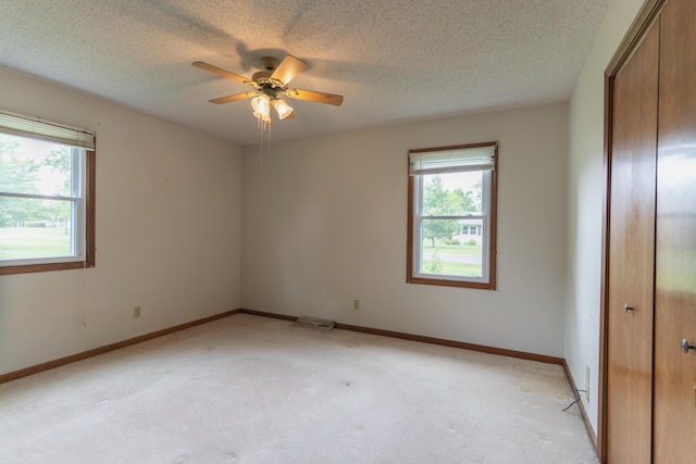 606 Wientz St, Moberly, MO 65270 - unfurnished bedroom with multiple windows, a closet, light colored carpet, and a textured ceiling