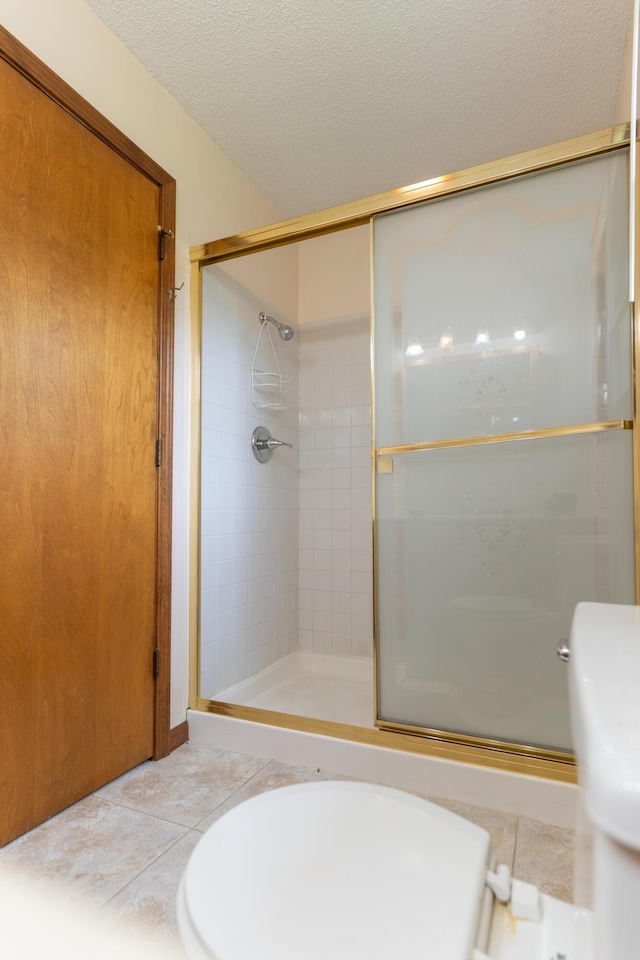 606 Wientz St, Moberly, MO 65270 - full bath featuring a shower stall, toilet, tile patterned flooring, and a textured ceiling