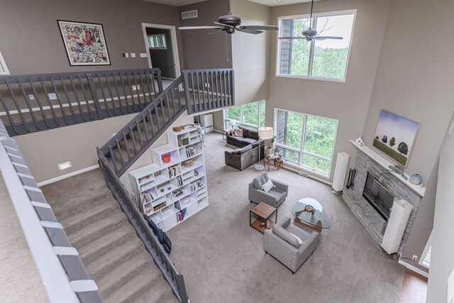 2416 Cimarron Dr, Columbia, MO 65203 - living area featuring a stone fireplace, a high ceiling, baseboards, stairway, and carpet