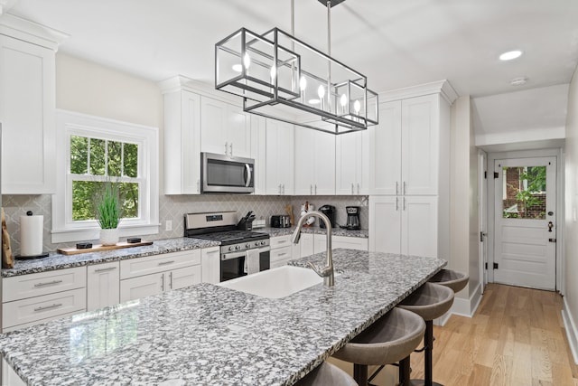 303 S Glenwood Ave, Columbia, MO 65203 - kitchen featuring appliances with stainless steel finishes, light wood-style floors, an island with sink, white cabinets, and recessed lighting