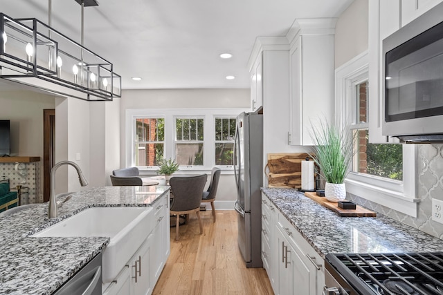 303 S Glenwood Ave, Columbia, MO 65203 - kitchen with appliances with stainless steel finishes, white cabinetry, light wood-style flooring, light stone countertops, and decorative light fixtures