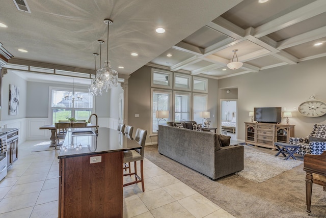 1904 Talco Dr, Columbia, MO 65201 - kitchen with a breakfast bar, a chandelier, a center island with sink, beamed ceiling, and light tile patterned flooring