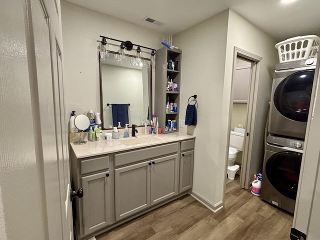 11630 N Varnon School Rd, Hallsville, MO 65255 - bathroom featuring stacked washer and clothes dryer, wood finished floors, toilet, and vanity