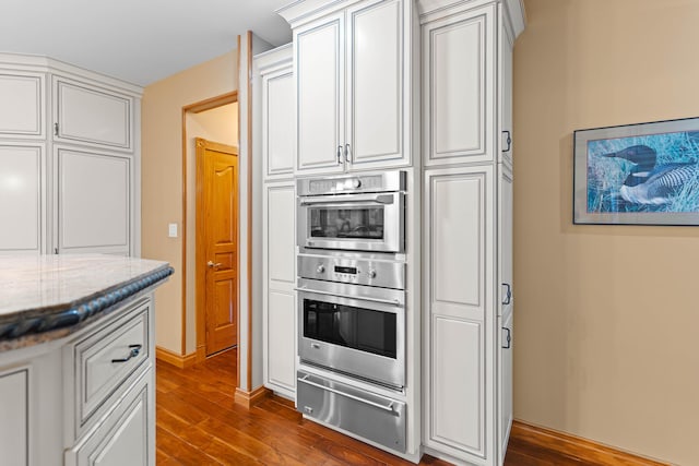 70 E High Point Ln, Columbia, MO 65203 - kitchen featuring a warming drawer, double oven, dark wood-style floors, and light stone countertops