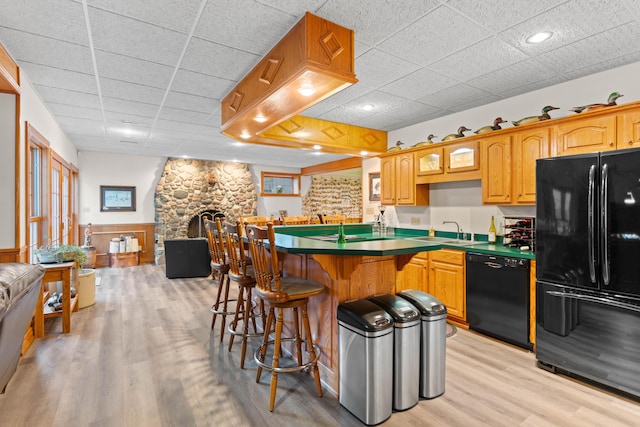 70 E High Point Ln, Columbia, MO 65203 - kitchen with black appliances, a sink, a breakfast bar, a drop ceiling, and light wood-style floors