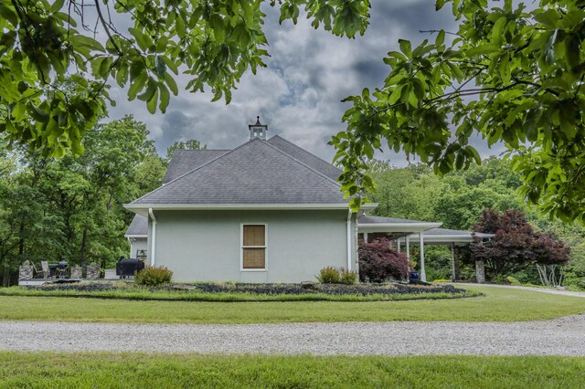 70 E High Point Ln, Columbia, MO 65203 - view of side of home featuring stucco siding, a lawn, a shingled roof, and a carport