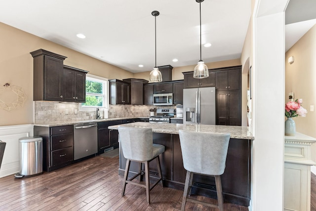 128 Cedar Falls Ct, Columbia, MO 65203 - kitchen featuring stainless steel appliances, dark brown cabinets, dark wood-type flooring, a peninsula, and light stone countertops
