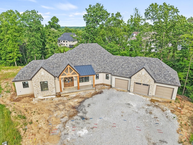 7200 Rudchester Ct, Columbia, MO 65203 - view of front of home with stone siding, a garage, a standing seam roof, gravel driveway, and metal roof