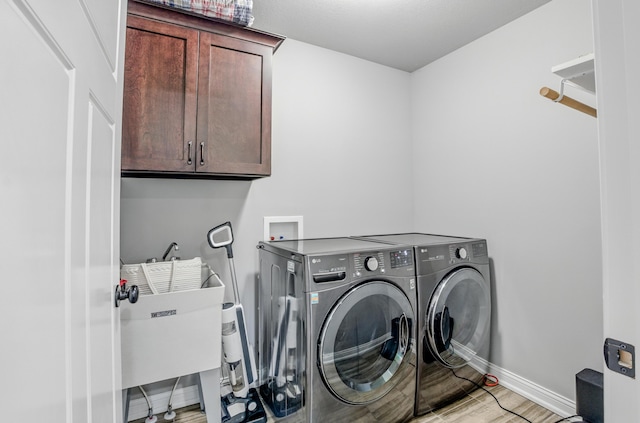 602 E Old Hawthorne Dr, Columbia, MO 65201 - laundry area featuring cabinet space, washing machine and clothes dryer, baseboards, and light wood-style flooring