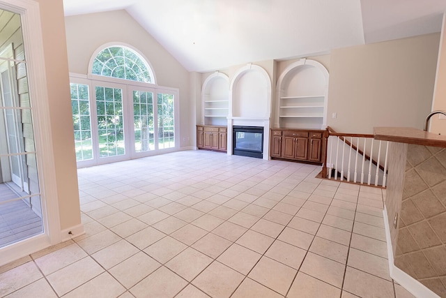 2409 Wild Oak Ct, Columbia, MO 65201 - unfurnished living room with lofted ceiling, a glass covered fireplace, built in shelves, and light tile patterned flooring