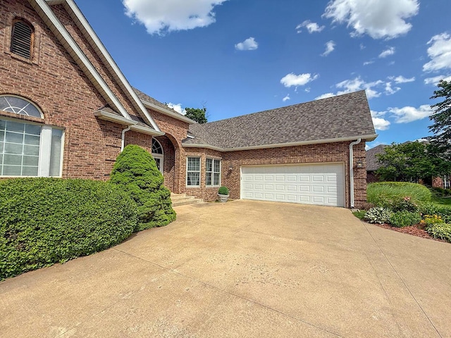 2409 Wild Oak Ct, Columbia, MO 65201 - view of front facade featuring driveway, brick siding, roof with shingles, and an attached garage