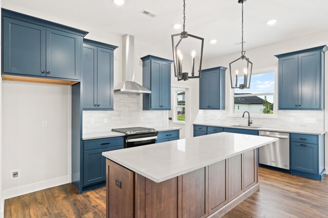 6505 Cromford Ln, Columbia, MO 65201 - kitchen with wall chimney range hood, appliances with stainless steel finishes, blue cabinets, a sink, and recessed lighting
