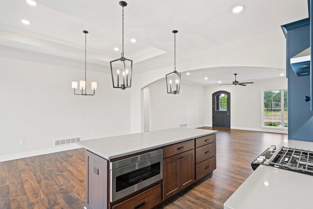 6505 Cromford Ln, Columbia, MO 65201 - kitchen featuring arched walkways, recessed lighting, stainless steel microwave, dark wood-style flooring, and a tray ceiling