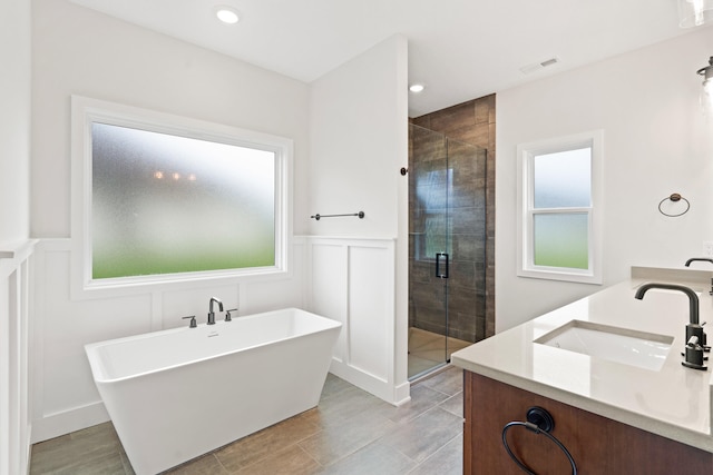 6505 Cromford Ln, Columbia, MO 65201 - bathroom featuring a freestanding tub, healthy amount of natural light, a shower stall, a decorative wall, and double vanity