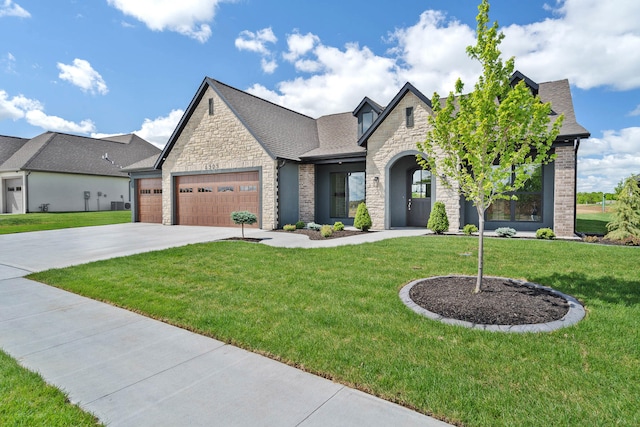 6505 Cromford Ln, Columbia, MO 65201 - french country style house featuring stone siding, an attached garage, a front lawn, driveway, and roof with shingles