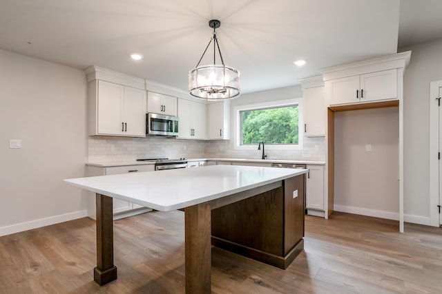 4000 S Felicity Ln, Columbia, MO 65203 - kitchen featuring appliances with stainless steel finishes, a sink, tasteful backsplash, a kitchen island, and white cabinets