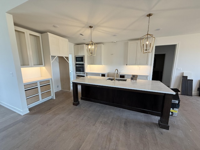 5915 Ivory Ln, Columbia, MO 65201 - kitchen featuring appliances with stainless steel finishes, a sink, white cabinetry, light wood-type flooring, and a kitchen island with sink