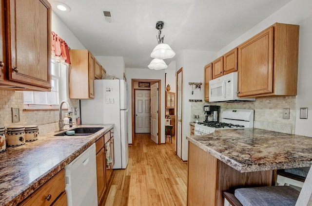 1402 Jean Rae Dr, Columbia, MO 65203 - kitchen with white appliances, a sink, light wood-style flooring, a breakfast bar area, and decorative backsplash