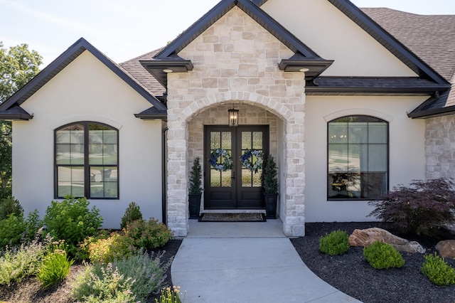 7501 Kirby Knowle Ct, Columbia, MO 65203 - view of exterior entry featuring stone siding, french doors, stucco siding, and roof with shingles