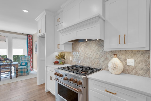 7501 Kirby Knowle Ct, Columbia, MO 65203 - kitchen with high end stainless steel range oven, light wood-style flooring, white cabinetry, custom exhaust hood, and decorative backsplash