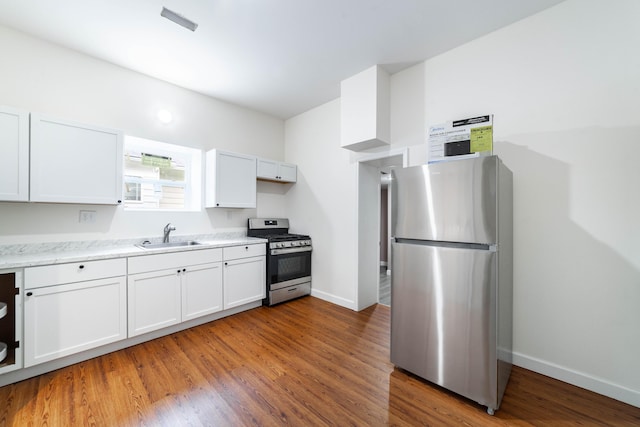 210 Oaklawn Ave, Fayette, MO 65248 - kitchen with stainless steel appliances, a sink, baseboards, wood finished floors, and white cabinets