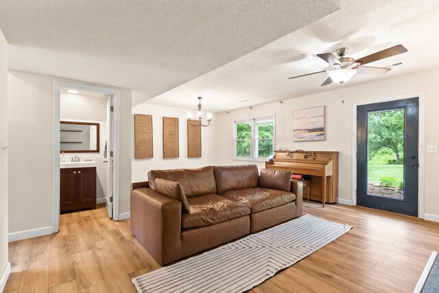 5700 Wilhite Rd, Columbia, MO 65202 - living area featuring light wood-style floors, a chandelier, a ceiling fan, a textured ceiling, and baseboards