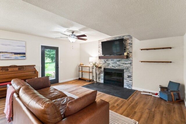 5700 Wilhite Rd, Columbia, MO 65202 - living room with wood finished floors, baseboards, a ceiling fan, a fireplace, and a textured ceiling