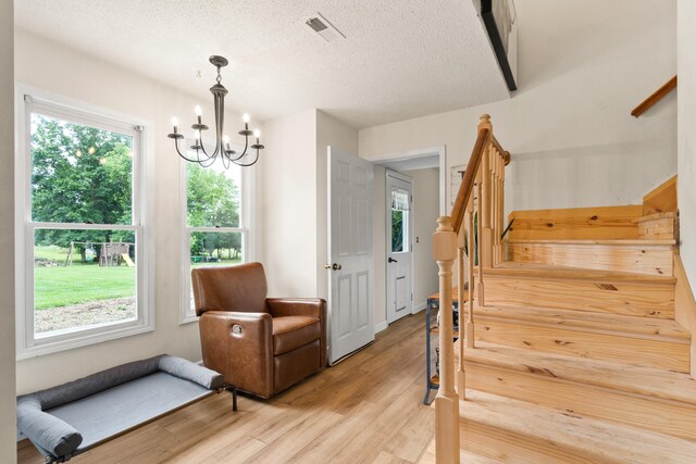 5700 Wilhite Rd, Columbia, MO 65202 - living area featuring stairs, plenty of natural light, light wood-type flooring, a chandelier, and a textured ceiling