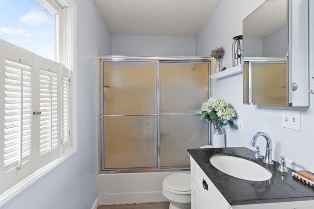 5700 Wilhite Rd, Columbia, MO 65202 - full bathroom with plenty of natural light, toilet, vanity, enclosed tub / shower combo, and a textured ceiling
