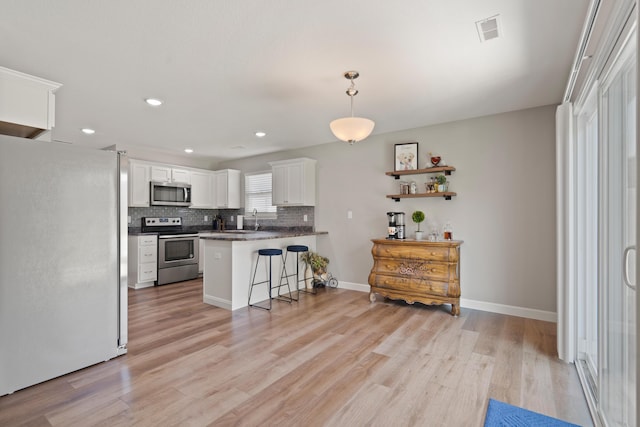 5817 Geyser Blvd, Columbia, MO 65202 - kitchen featuring stainless steel appliances, a kitchen breakfast bar, a peninsula, white cabinetry, and light wood-type flooring
