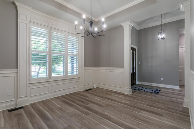 2016 Devonshire Dr, Columbia, MO 65203 - unfurnished dining area featuring a chandelier, a decorative wall, wood finished floors, crown molding, and wainscoting