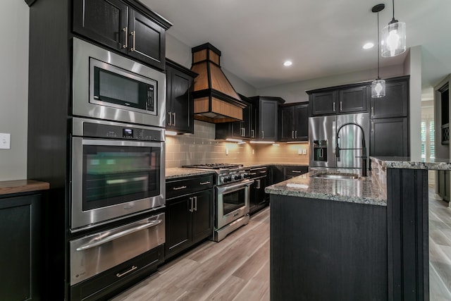 2016 Devonshire Dr, Columbia, MO 65203 - kitchen featuring appliances with stainless steel finishes, a warming drawer, dark cabinetry, light stone countertops, and custom exhaust hood