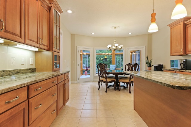 203 Foxwood Ct, Columbia, MO 65203 - kitchen featuring a chandelier, stainless steel microwave, light stone counters, brown cabinetry, and hanging light fixtures