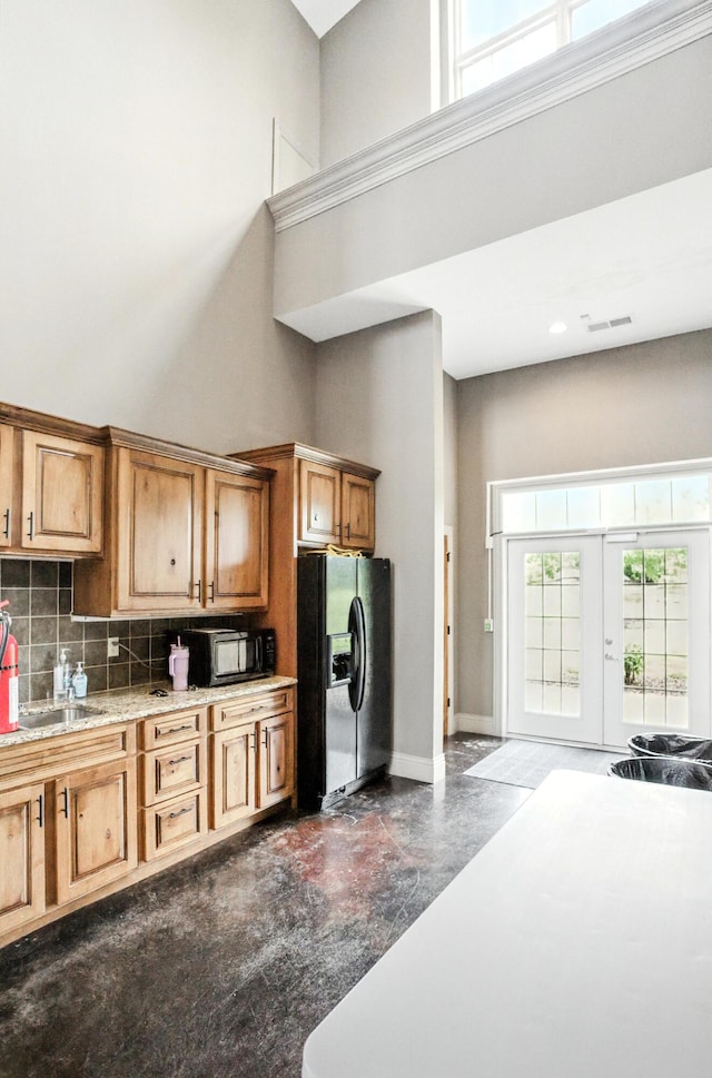 1600 Andretti Cir, Columbia, MO 65201 - kitchen with a high ceiling, black appliances, backsplash, brown cabinets, and light stone countertops