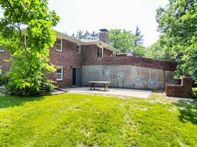 4705 Roemer Rd, Columbia, MO 65202 - back of property featuring a chimney, a yard, a patio area, and brick siding