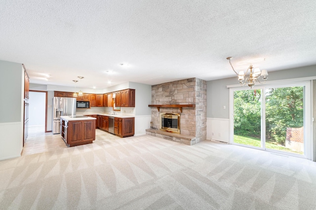 4705 Roemer Rd, Columbia, MO 65202 - unfurnished living room featuring wainscoting, light carpet, a textured ceiling, a chandelier, and a stone fireplace