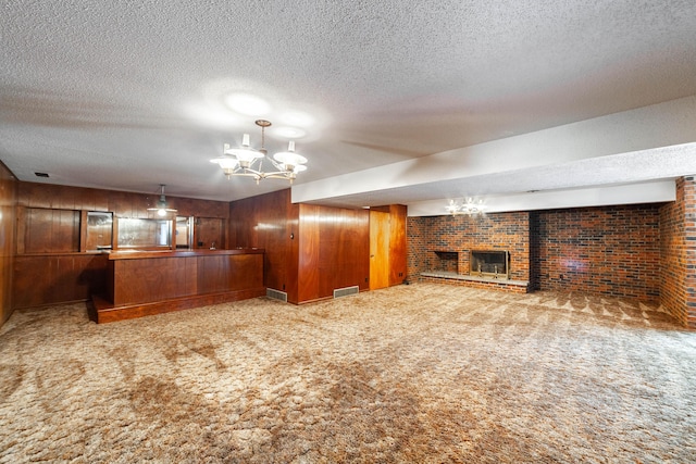 4705 Roemer Rd, Columbia, MO 65202 - unfurnished living room with carpet floors, a textured ceiling, a chandelier, a brick fireplace, and wooden walls