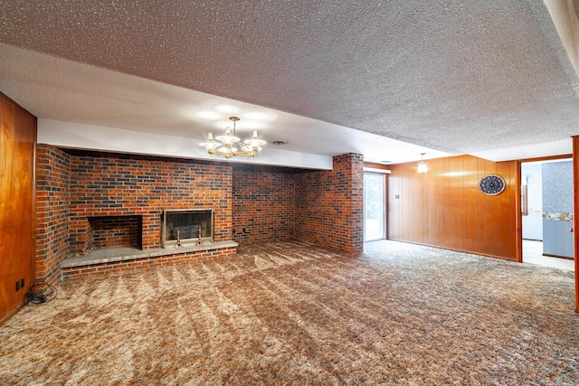 4705 Roemer Rd, Columbia, MO 65202 - unfurnished living room with wood walls, carpet, a textured ceiling, a chandelier, and a brick fireplace