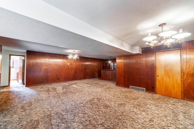 4705 Roemer Rd, Columbia, MO 65202 - basement with a chandelier, wood walls, a textured ceiling, and carpet flooring