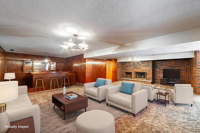 4705 Roemer Rd, Columbia, MO 65202 - carpeted living area with a chandelier, wood walls, a fireplace, and a textured ceiling