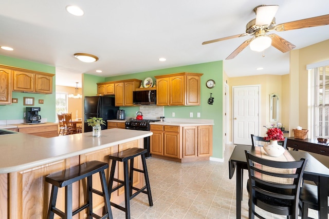 9050 Hartley Rd, Hallsville, MO 65255 - kitchen with black appliances, light countertops, a breakfast bar area, ceiling fan, and a peninsula